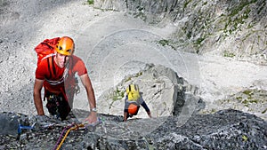 Two male rock climbers on a granite climbing route in the high alpine peaks of southeastern Switzerland