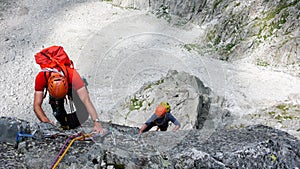 Two male rock climbers on a granite climbing route in the high alpine peaks of southeastern Switzerland