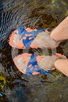 Two male's feet with orange and blue sandals in