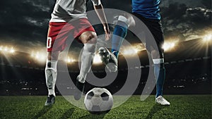 Two male soccer, football players dribbling ball at the stadium during sport match on dark sky background.