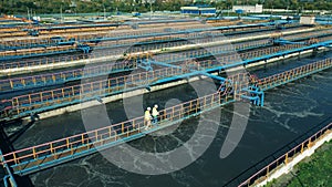 Two male specialists inspecting a modern wastewater treatment plant