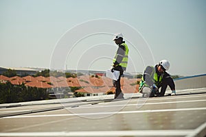 Two male technicians install solar panels