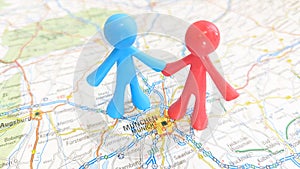 Two male toy figures holding hands on a map of Munich Germany