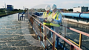 Two male wastewater operators taking water samples for analysis
