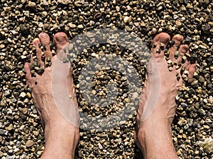 Two male white feet sunbathed on the sand of the beach