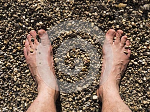 Two male white feet sunbathed on the sand of the beach