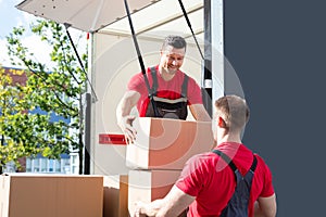 Two Male Worker Loading The Cardboard Boxes In Moving Truck