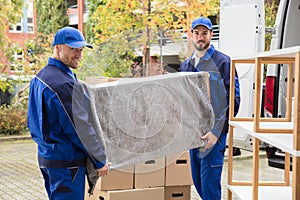 Two Male Worker Unloading Furniture From Truck