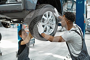 Two male workers fixes wheel, car service