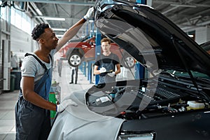 Two male workers inspects engine, car service