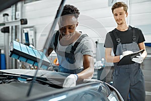 Two male workers repairs engine, car service