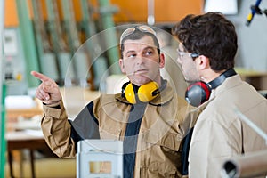 Two male workers talking in carpentry workshop