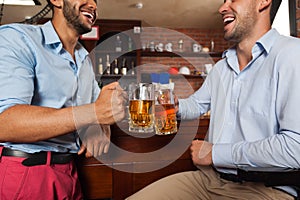 Two Man In Bar Clink Glasses Toasting Sit At Table, Drinking Beer Hold Mugs Close Up