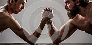 Two man`s hands clasped arm wrestling, strong and weak, unequal match. Heavily muscled bearded man arm wrestling a puny