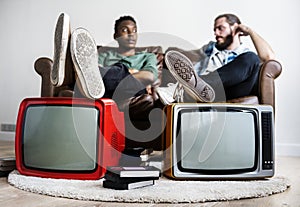 Two man sitting and two retro television