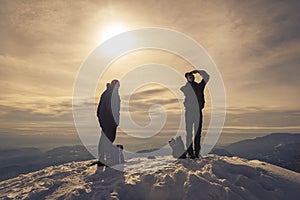 Two man on snow the summit of mountain during sunset in winter