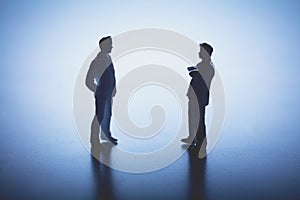 Two man standing face to face on white background.