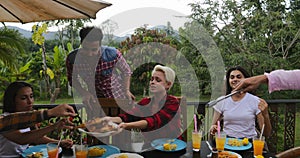 Two Man Taking Food From Barbecue People Sitting At Table Young Friends Group Gathering On Summer Terrace Having Party