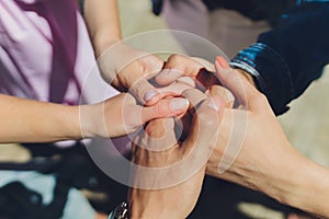 Two man and three women holding hands on a table implying a polyamory relationship or love triangle. photo