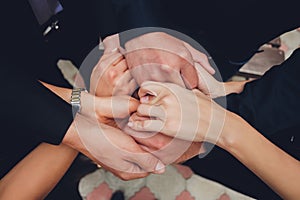Two man and three women holding hands on a table implying a polyamory relationship or love triangle. photo