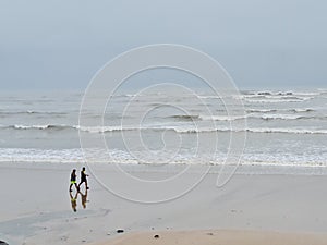 Two man walk when Small ocean waves breaking on beach