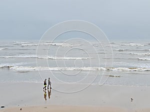 Two man walk when Small ocean waves breaking on beach