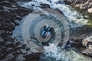 Two man on whitewater catamaran are going through the rapid on the mountain river in early spring