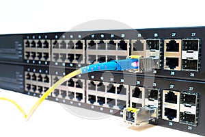 Two managed stackable Gigabit Ethernet switches with a connected optical wires are  on a white background