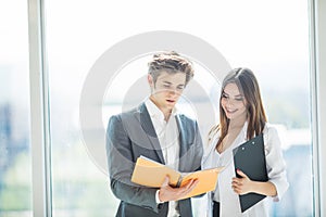 Two managers discussing profit. Group of business people working together in office discussing over notebook. Young startup.