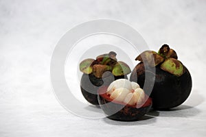 Two mangosteen and one peel on white background.