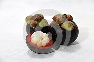 Two mangosteen and one peel on white background.