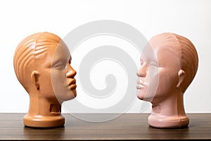 Two Mannequin Heads face to each other on wooden table