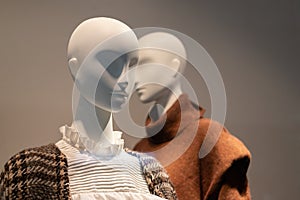 Two mannequins in a shop window dressed in warm clothes for autumn and winter. Seasonal sale