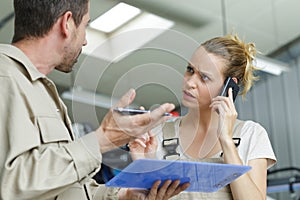 Two manual workers in disagreement while speaks woman on telephone