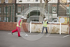 Two manual workers playing football