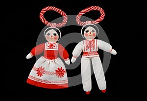 two martenitsa dolls in red and white clothing with red ribbons