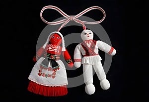 two martenitsa dolls in traditional costumes are hanging from a ribbon