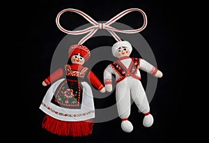 two martenitsa dolls in traditional costumes hanging from a ribbon