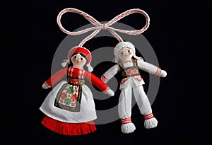 two martenitsa dolls in traditional costumes are hanging from a ribbon