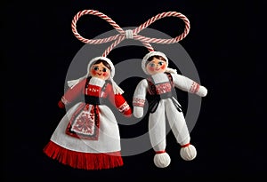 two martenitsa dolls in traditional costumes hanging from a rope