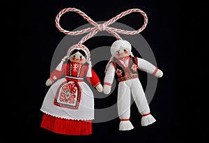 two martenitsa dolls in traditional costumes hanging from a rope