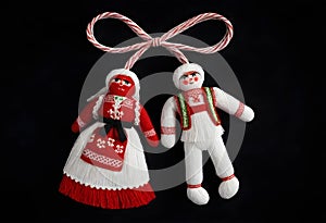 two martenitsa dolls in traditional costumes hanging from a rope