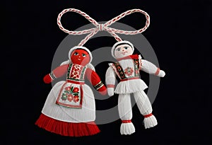 two martenitsa dolls in traditional costumes are hanging from a rope
