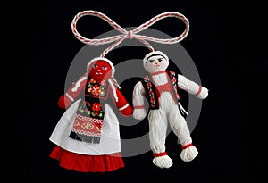 two martenitsa dolls in traditional costumes are hanging from a rope