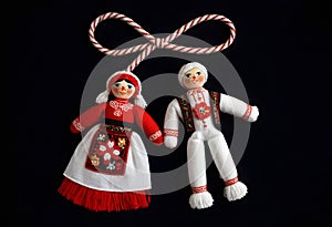 two martenitsa dolls in traditional costumes are hanging from a rope