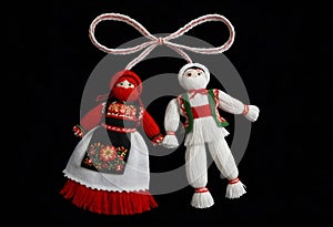 two martenitsa dolls in traditional costumes are hanging from a string