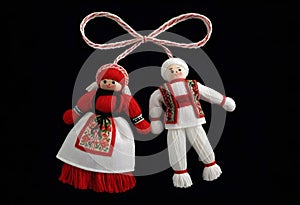 two martenitsa dolls in traditional costumes are hanging from a string