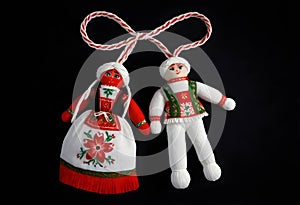 two martenitsa dolls in traditional costumes hanging from a string isolated on black background