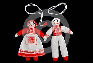 two martenitsa dolls in traditional russian clothing are on a black background