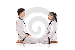 Two martial art practitioners sitting face to face on their knees, full length